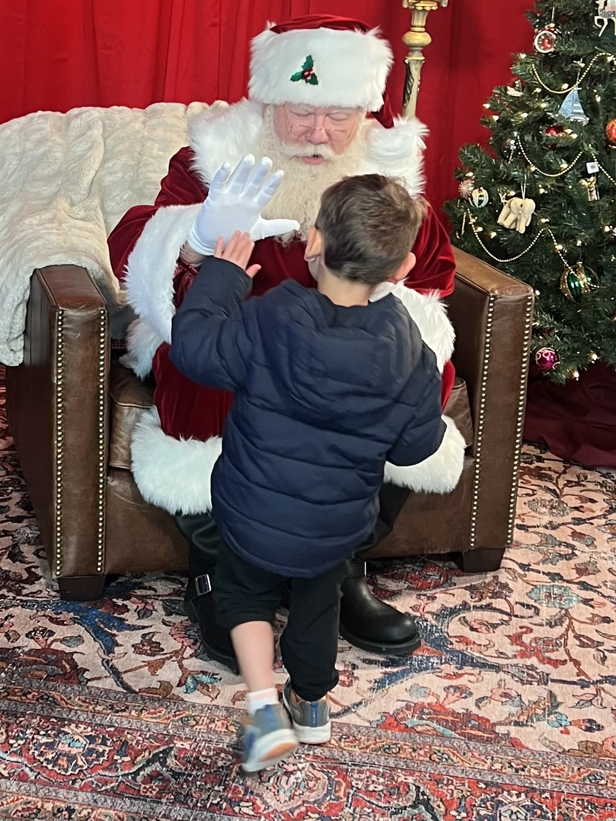 A child reaches up to high-five Santa