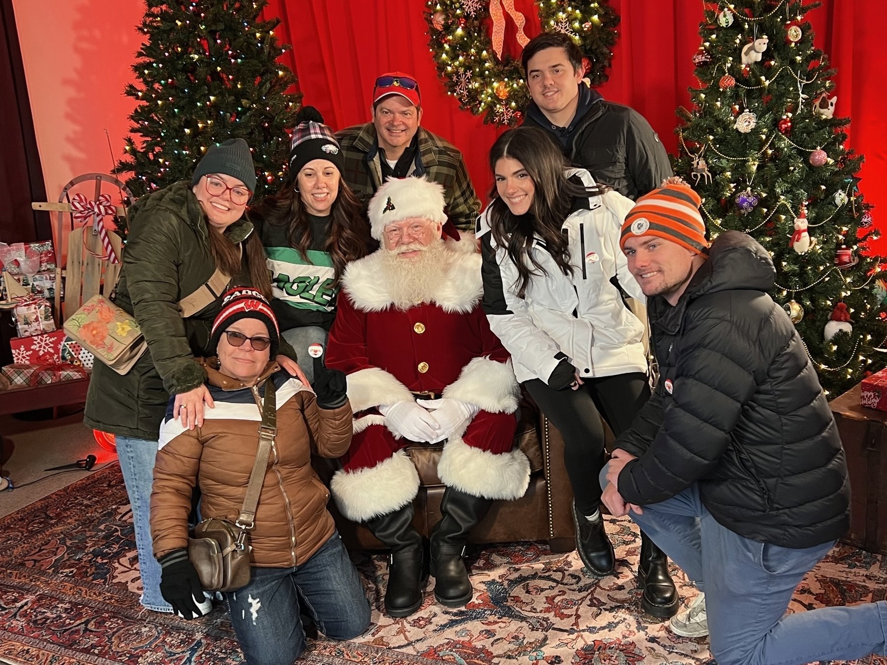 A group of visitors posing with Santa among decorated trees