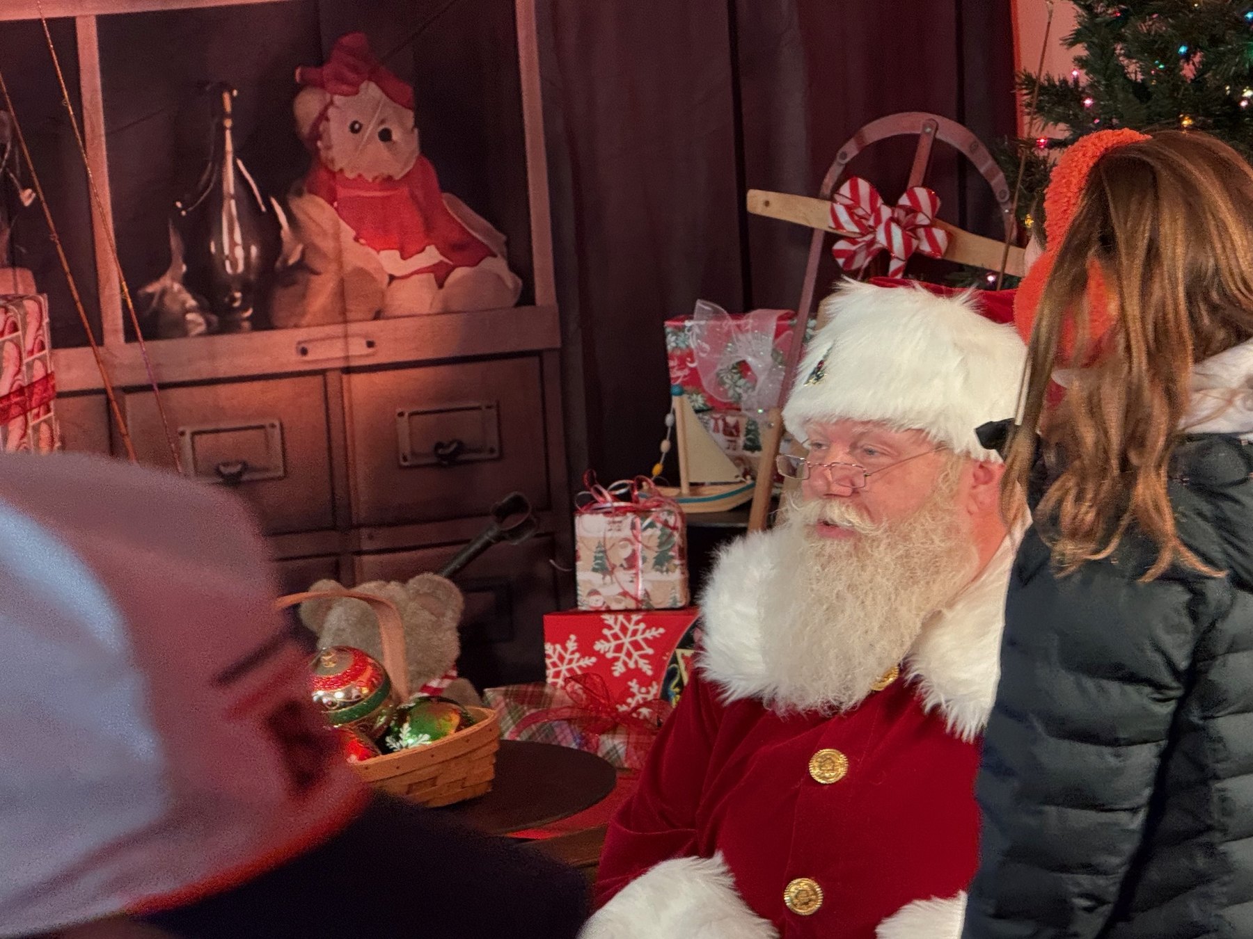 Santa seated beside a child and an adult